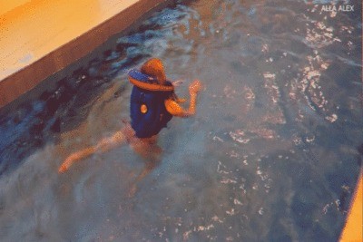 Alla swims in the pool in an inflatable vest.